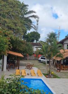 a pool with lounge chairs and a table and a car at Pousada Varanda do Sol in Arraial d'Ajuda