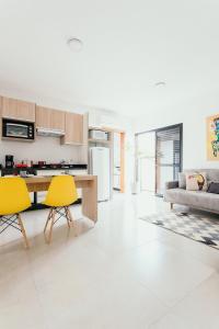 een keuken en een woonkamer met gele stoelen en een tafel bij Apartamentos modernos e aconchegantes no centro. in Poços de Caldas
