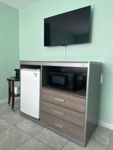a tv on top of a entertainment center with a refrigerator at Royal Canadian Motel in Wildwood