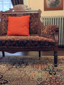 a couch with an orange pillow on top of a rug at The Vistula Rose B & B in Toledo