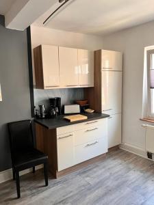 uma cozinha com armários brancos e uma cadeira preta em Ferienhaus Herztor em Bad Bibra