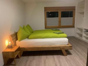 a bedroom with a bed with green pillows and a window at B&B Kalbermatter in Turtmann