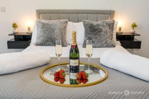a bottle of champagne and two glasses on a bed at Townhouse near BEACH, Sleeps 8, Garden & Parking - Carbery Lux in Bournemouth