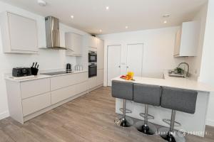 a kitchen with white cabinets and a counter top at Townhouse near BEACH, Sleeps 8, Garden & Parking - Carbery Lux in Bournemouth