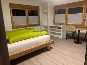 ein Schlafzimmer mit einem Bett mit einer grünen Decke darauf in der Unterkunft B&B Kalbermatter in Turtmann