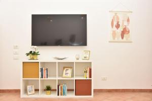 Home in Certosa Pigneto con parcheggio في روما: غرفة معيشة مع تلفزيون على رف كتاب أبيض