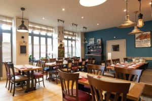 un comedor con mesas y sillas en un restaurante en Logis - Hôtel Le Caddy, en Le Touquet-Paris-Plage