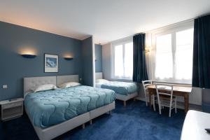 a bedroom with two beds and a table and a desk at Logis - Hôtel Le Caddy in Le Touquet-Paris-Plage