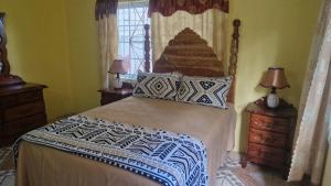 a bedroom with a bed and two lamps and a window at Bev's Rosevilla in Montego Bay