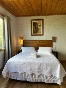 a bedroom with a white bed with a wooden ceiling at Pousada do Rei Arthur in Lavras Novas
