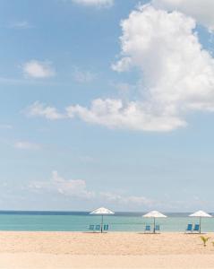 três cadeiras e guarda-sóis numa praia com o oceano em Netuno Beach Hotel em Fortaleza