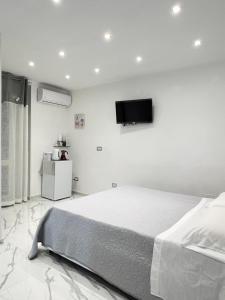 um quarto branco com uma cama e uma televisão na parede em B&B Marika Toledo em Nápoles