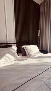 un letto con lenzuola e cuscini bianchi in una camera da letto di PARK LUX II a Vršac