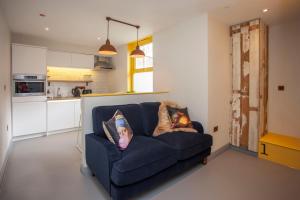 ein Wohnzimmer mit einer blauen Couch mit Kissen in der Unterkunft higgihaus Apartment 4 Clare Street Aparthotel Central Location in Bristol