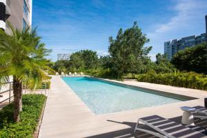a large swimming pool with lounge chairs and trees at 04063 New Deluxe Unit Signature Condominium US Consulate in Mérida