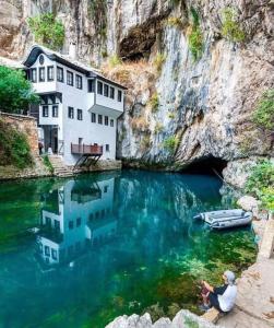 a house in the water with a boat in it at Lovely Bosnian Home in Mostar