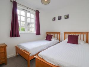 two beds in a room with a window at Minions Cottage in Bodmin