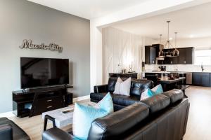 a living room with a leather couch and a television at Diamond Retreat Townhome 7 Beds 3 mi to Downtown in Nashville