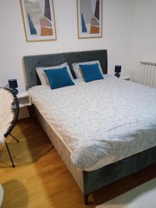 1 dormitorio con 1 cama grande con almohadas azules en Studio App Bulevar - free parking, en Sarajevo