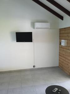 a room with a white wall with a television on it at Zaboka delair in Sainte-Anne