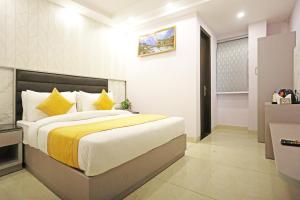 Un dormitorio con una cama grande con almohadas amarillas y blancas en Frankstay By Hotel Mayfair Residency en Nueva Delhi
