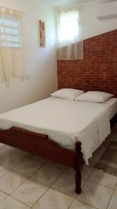 a large bed in a room with a brick wall at La cabane de Josephine in Le Lamentin