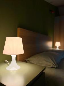 a white lamp sitting on a table next to a bed at Mansarda Moderna in Lunigiana con Giardino in Aulla