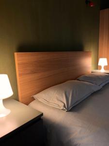 a bed with a wooden headboard in a room at Mansarda Moderna in Lunigiana con Giardino in Aulla