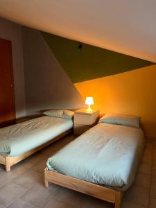 two beds in a room with a yellow wall at Mansarda Moderna in Lunigiana con Giardino in Aulla