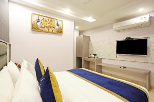 um quarto com uma cama grande e uma televisão de ecrã plano em Frankstay By Hotel Mayfair Residency em Nova Deli
