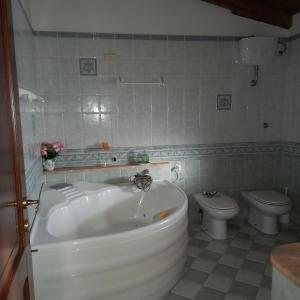 een badkamer met een wit bad en een toilet bij Casa Bia Mara IUN SU172600 in Villanovaforru