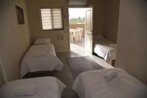 a room with three beds and a window with a table at חאן דרך העץ - חדרי מטיילים in Shadmot Devora