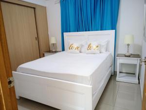 a white bed in a room with blue curtains at Confortable apto. en Boca Chica in Boca Chica