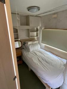 a small bedroom with a bed and a desk at Lake District Caravan in Cockermouth