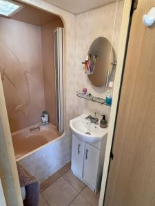 a bathroom with a sink and a mirror and a tub at Lake District Caravan in Cockermouth