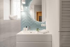 La salle de bains est pourvue d'un lavabo et d'un miroir. dans l'établissement Sanhaus Apartments - Apartament LIDO - 300 m od plaży, à Sopot