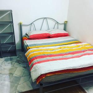 ein Bett mit einer bunten gestreiften Decke drauf in der Unterkunft Hz Homestay Bertam in Kepala Batas
