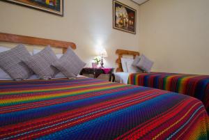 a hotel room with two beds with colorful blankets at Posada Do&ntilde;a Luisa in Antigua Guatemala