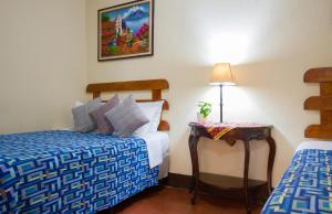 een slaapkamer met 2 bedden en een tafel met een lamp bij Posada Doña Luisa in Antigua Guatemala