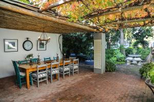 a wooden table and chairs under a pergola at 5 Konings Guesthouse in Paarl