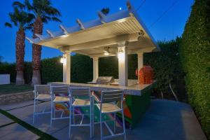 a patio with a bar with stools under a pergola at Pineapple Splash! Complete Privacy! Salt Pool! in Palm Springs