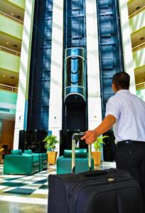 a man standing in an airport with a suitcase at Hotel Tropical Executive Flat 020 in Manaus