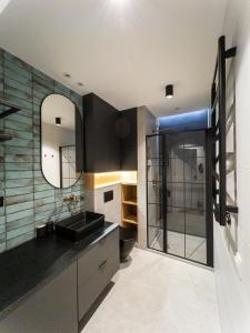 een badkamer met een zwarte wastafel en een spiegel bij Mint Apartments Gdańsk DOKI in Gdańsk +88 foto's