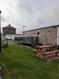 einem Wohnwagen mit Picknicktisch und einem Haus in der Unterkunft 136, Port Haverigg in Millom