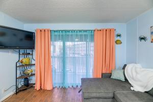 a living room with a couch and a flat screen tv at Corpus Christi Condo with Balcony and Beach Views! in Corpus Christi