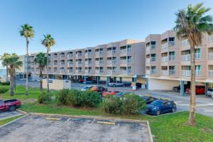 an apartment building with cars parked in a parking lot at Corpus Christi Condo with Balcony and Beach Views! in Corpus Christi