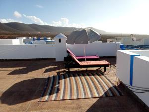 eine Terrasse mit einem Sonnenschirm, einem Stuhl und einem Teppich in der Unterkunft Kasbah lagzira in Sidi Borja