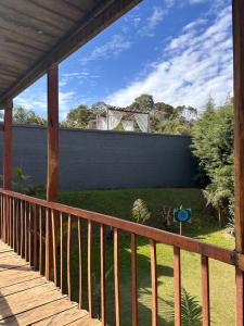 une terrasse couverte en bois avec une clôture et une cour dans l'établissement Pousada do Rei Arthur, à Lavras Novas