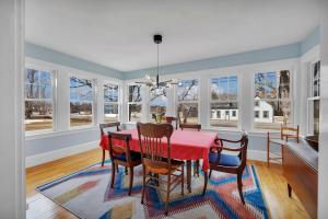 a dining room with a red table and chairs and windows at Sugar Maple Farm near Acadia - 4 Bedrooms, 5 Beds in Lamoine Corner