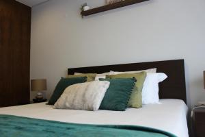 a bedroom with a bed with green and white pillows at Apartament F&M in Braga